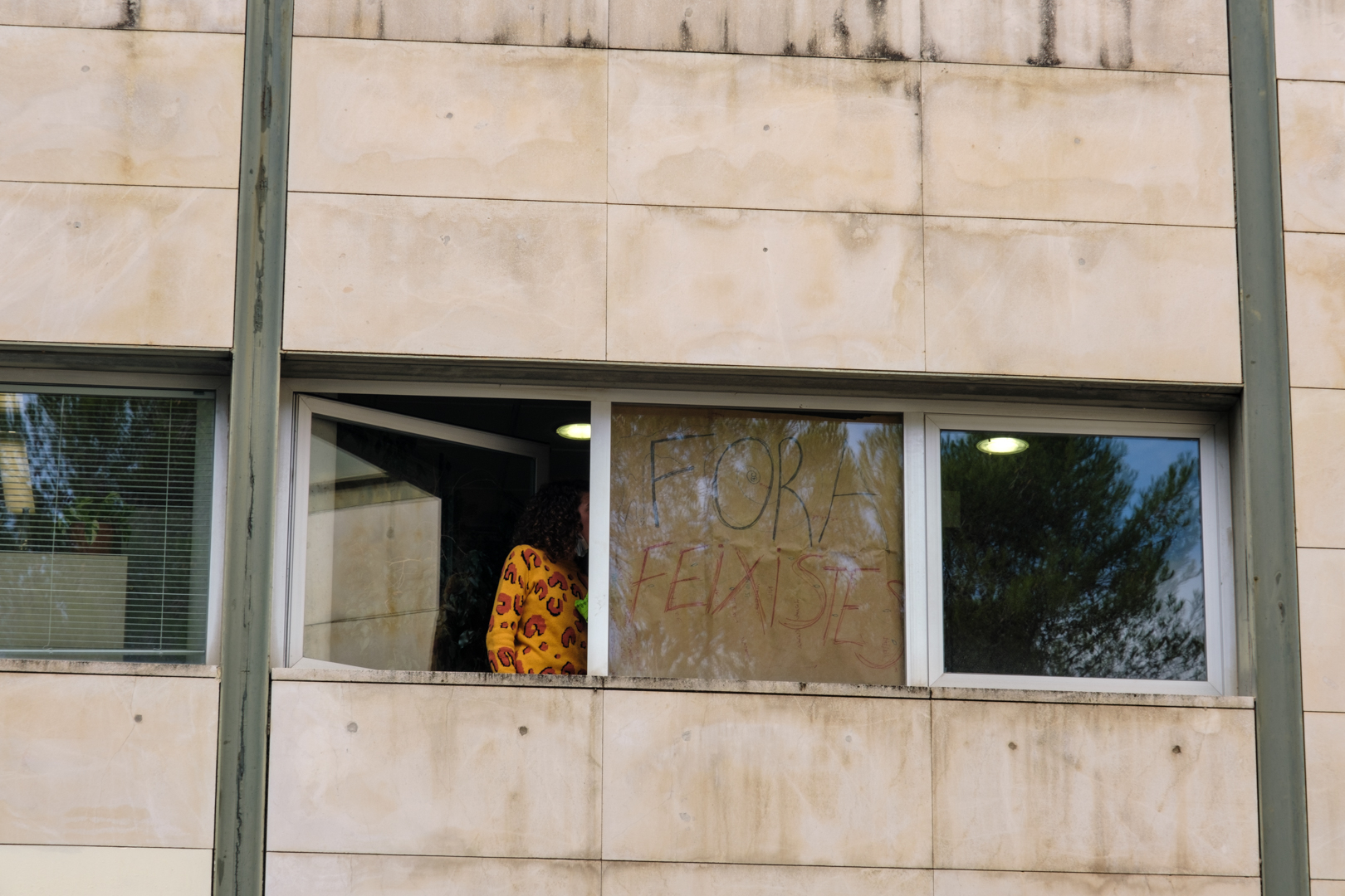 Un cartell diu “Fora Feixistes” des d'una finestra de l'edifici Àgora